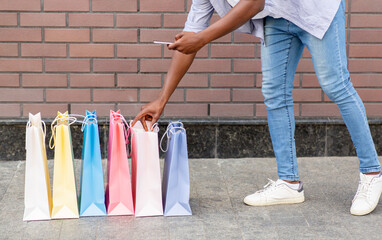 Report on purchases. African american guy checks staff and makes photo in bags