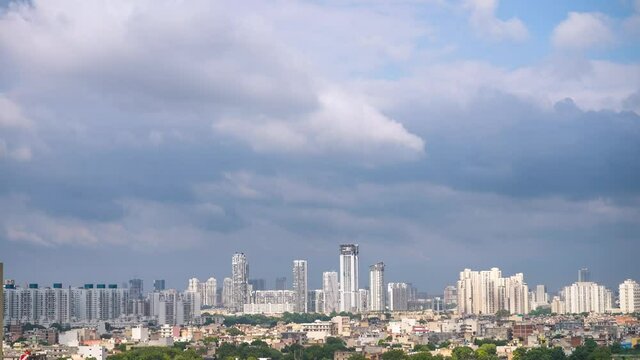 Aerial timelapse of gurgaon delhi cityscape with monsoon clouds casting shadows on high rise apartments and buildings showing passage of time and rapid growth of real estate and infrastructure