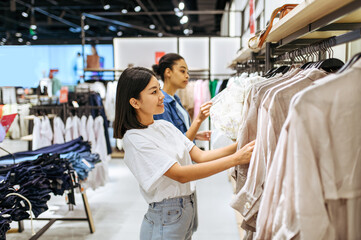 Two girlfriends choosing clothes in clothing store