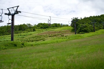 Obraz premium The ropeway at the hill in summer. The view of Japanese ski resort.
