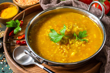 Indian cuisine. Traditional Indian spicy lentil puree soup with herbs on a dark background.