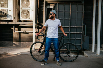 Young bearded hipster guy wearing white blank t-shirt with bicycle . Mock-up for print. T-shirt template. - obrazy, fototapety, plakaty