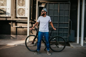 Fotobehang Young bearded hipster guy wearing white blank t-shirt with bicycle . Mock-up for print. T-shirt template. © San4ezz007