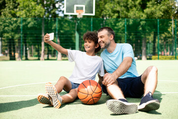 Happy dad and son taking selfie using smart phone
