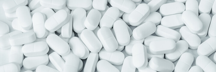 Medical background of many white capsule tablets or pills on the table. Full frame background....