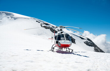 White and red helicopter landed on snow in winter.