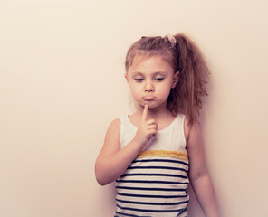 Thinking serious grimacing skeptical girl with finger under the face and have an idea. Closeup portrait with copy empty space toned background. Education