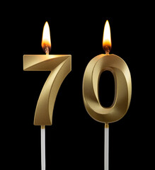 Burning golden birthday candles isolated on black background, number 70	