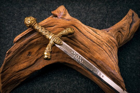 Knight's sword on the background of an old textured wooden driftwood of brown color