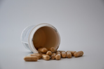 Close up medication bottle and natural pills spilled on white background. Medication and prescription pills flat lay background