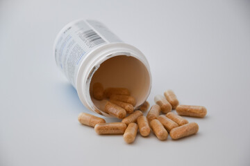Close up medication bottle and natural pills spilled on white background. Medication and prescription pills flat lay background