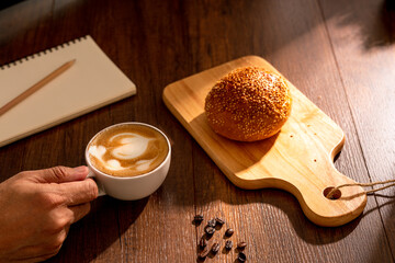 Cup of hot coffee with bread on wood background