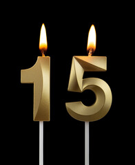 Burning golden birthday candles on black background, number 15	
