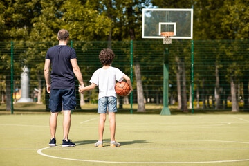 Man posing with son on basketball pitch back view