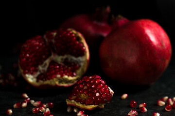 An open grenade on a black background next to a bottle. Pomegranate wine in the decanter next to the red pomegranate fruit