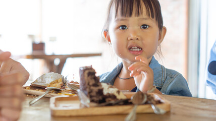 Portrait of a cute Asian girl after eating delicious chocolate cake in a restaurant with copy space for your text.