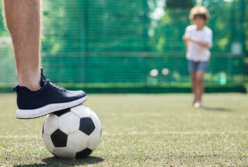 Player stepping on the soccer ball standing on green field