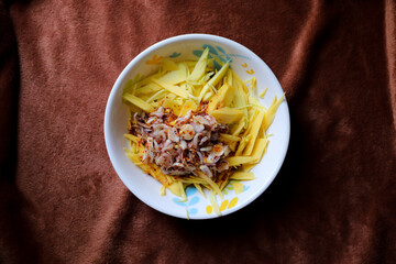 Thai food, Spicy green mango salad on Brown cloth background, Top view