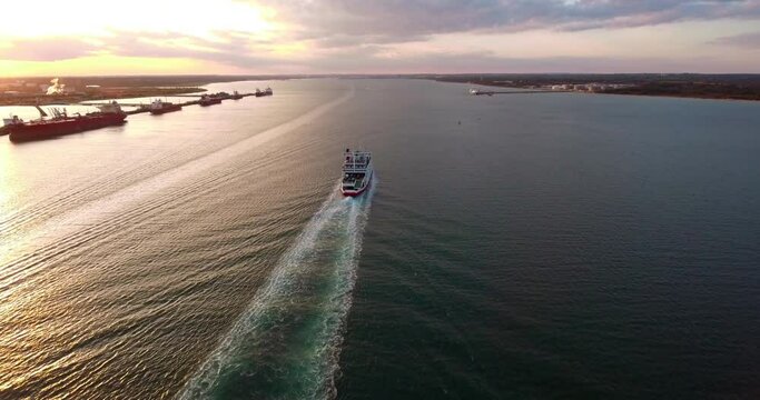 4K Aerial over the Solent Following an​ Isle of Wight ferry going up Southampton water during early evening sunset with small boats passing by.
