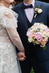 Happy bride and groom with bridal bouquet walking in garden on wedding day at summer. Wedding...