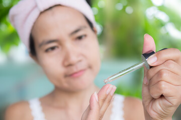 Close up drop of serum on finger with woman. Beauty and skin care concept. asian woman authentic.