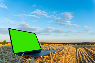Laptop in the autumn field with green chromakey screen