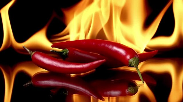 Hot red chili peppers in flames on a black background. Spicy food concept. Slow motion 120 fps