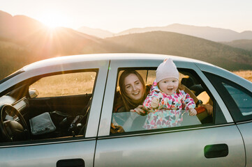 Happy family on the sunset in car. Mom and daughter - tourist girls. Toward adventure! Family enjoying road trip and autumn vacation. Holiday and travel concept. Closeup.