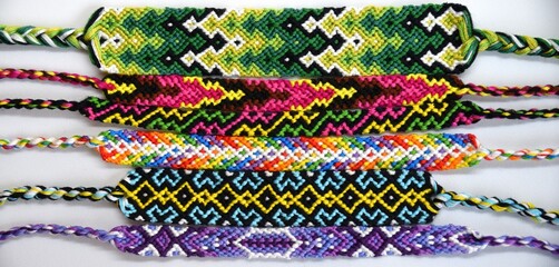 Many woven DIY friendship bracelets handmade of embroidery bright thread with knots on light background.