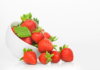 Fresh raw organic strawberries in white ceramic bowl plate on white background with berries next to it.