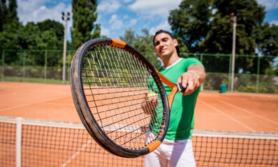 Portrait of young athletic man on tennis court.