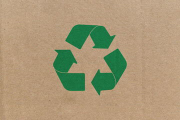 Green recycle symbol on cardboard background.