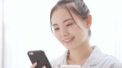 パジャマ姿でスマートフォンを操作している女性