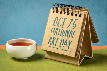 National Art Day (October 25) in a desktop calendar with a cup of tea against colorful handmade paper