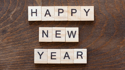 written "happy new year" with light wood letters on dark wood