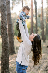 Portrait of happy Caucasian mother lifting and playing with her cute little son, enjoying their...