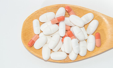 Fototapeta na wymiar White tablets in a wooden spoon, isolated on a white background, close-up