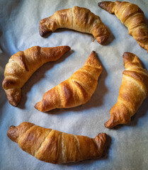 Homemade croissants on baking paper at the morning light.