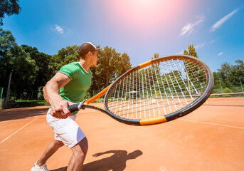 Young athletic man playing tennis on the court.