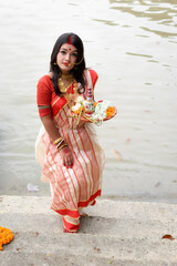 Portrait of beautiful Indian woman draped in traditional saree, adorned with gold jewellery holding...