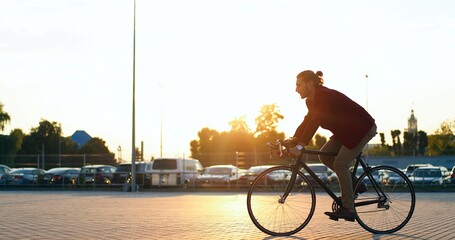 Caucasian male bike rider on sunset outdoors. Stylish handsome man riding bicycle and crossing car...