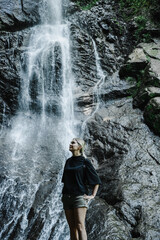Fototapeta premium young woman on the background of a mountain waterfall with a ponytail 