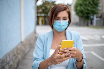 Woman with face mask using phone texting outdoor stock photo