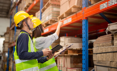Warehouse management team checking organization and distribution in storage shipping center.manager is showing a clipboard to a worker in a warehouse