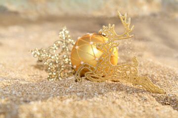 Christmas gold glitter decoration ball and reindeer on the tropical beach near ocean, a summer Christmas and winter holyday concept, selective focus. Merry Christmas and Happy New Year background