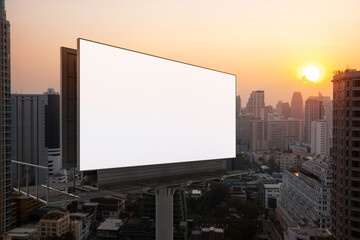 Blank white road billboard with Bangkok cityscape background at sunset. Street advertising poster, mock up, 3D rendering. Side view. The concept of marketing communication to promote or sell idea.