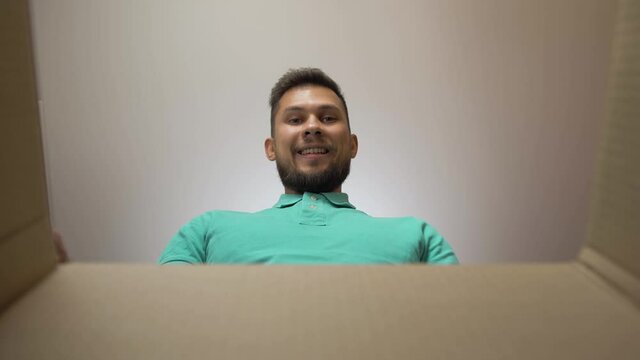 Young man POV opening carton box delivery and pulling out gift purchase. Male looking in box and happy to receiving products. Handsome man happy smiling after courier e-commerce delivery