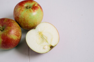 Flat-lay concept of red apples on a white wooden background, view from above, half apples