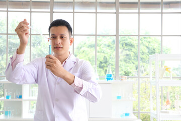 Obraz premium Asian scientists or chemists experiment with droplets of blue liquid chemicals in a laboratory.