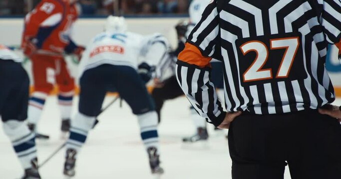 Hockey referee holding a puck in face off position. Front view.